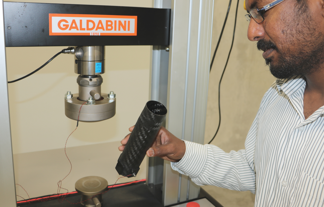 The poicture shows a man at the universal testing machine for the investigation of fiber-reinforced lightweight materials.