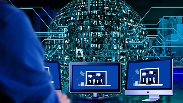 Representation of a sphere with many people on it, in front of it sits a person in front of three screens, of which only the arm is visible
